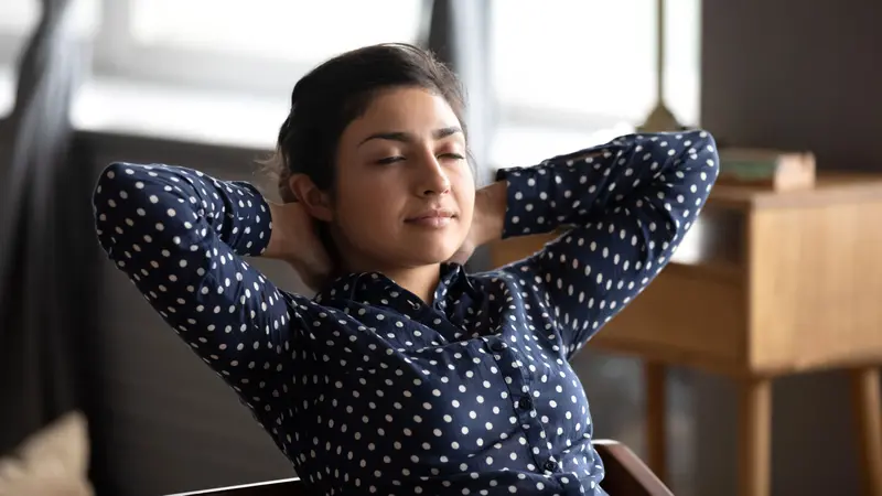 Calm relaxed Indian lady practicing breath work at home office Calm relaxed Indian lady practicing breath work at home office