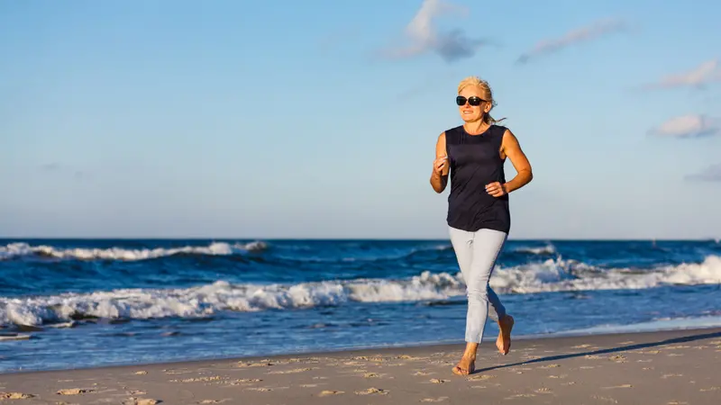 Middle-aged woman running on beach Middle-aged woman running on beach