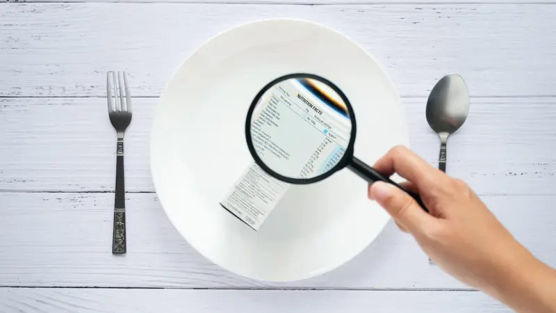 hand use the magnifying glass to zoom in to see the details of the nutrition facts label on the side of the consumer product box on white dish hand use the magnifying glass to zoom in to see the details of the nutrition facts label on the side of the consumer product box on white dish