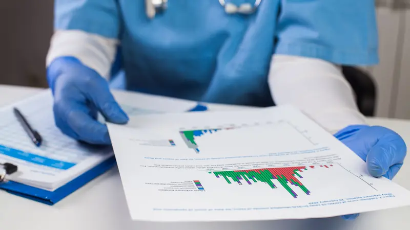 Doctor wearing protective gloves holding document chart analyzing graph data
