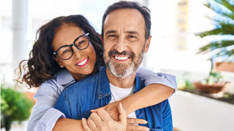 Middle age hispanic couple smiling and hugging each other 