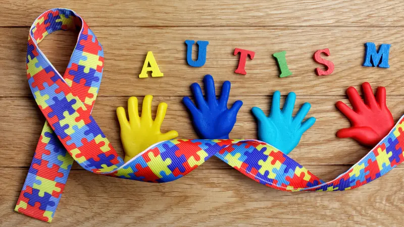 Autism awareness concept with colorful hands on wooden background.