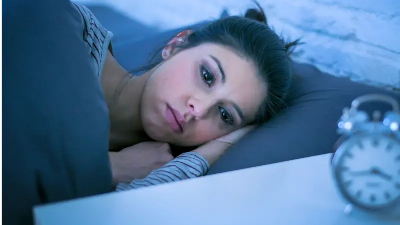 Sad and worried Latin woman unable to sleep at night lying on bed awake Sad and worried Latin woman unable to sleep at night lying on bed awake
