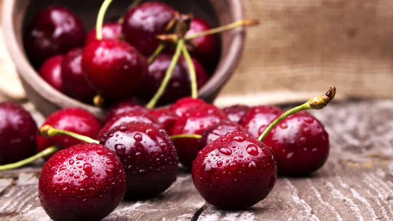 Cherries on wooden table with water drops macro background