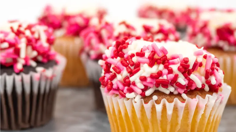 Tray Full of Vanilla and Chocolate Cupcakes Decorated with White Frosting and Red, White and Pink Sprinkles