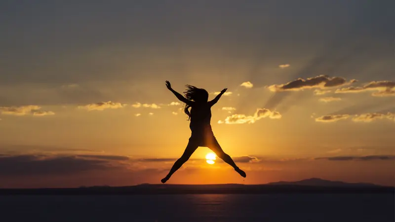 Woman jumping for joy and happines at sunset