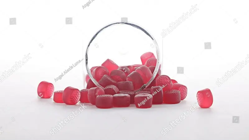 Red melatonin gummies in front with a white background