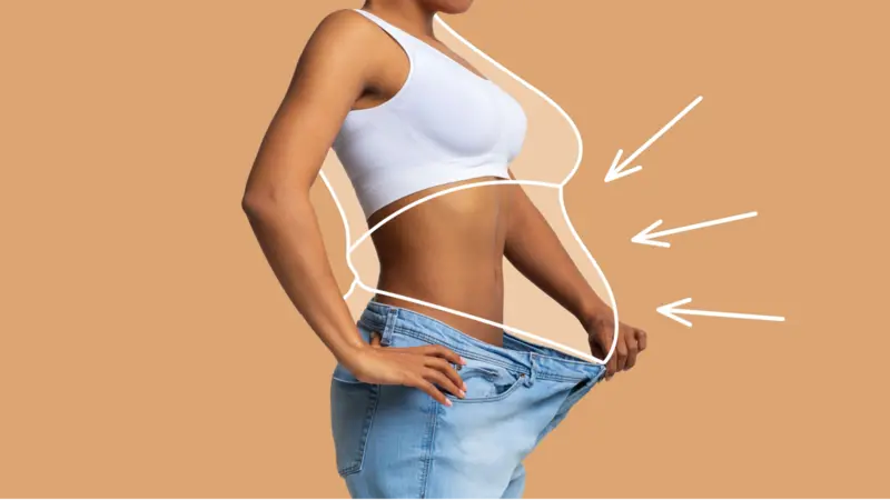 Young slim African American female in big jeans enjoy weight loss result with fat abstract body around, arrows isolated on beige wall background
