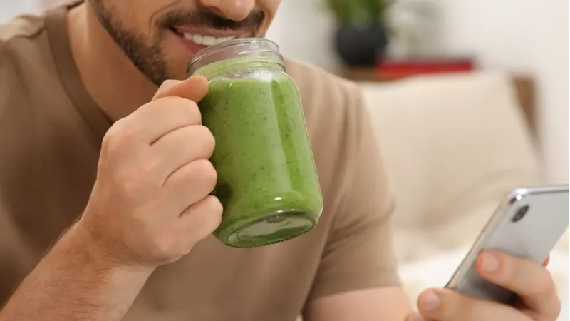 Happy man holding delicious fresh green smoothie