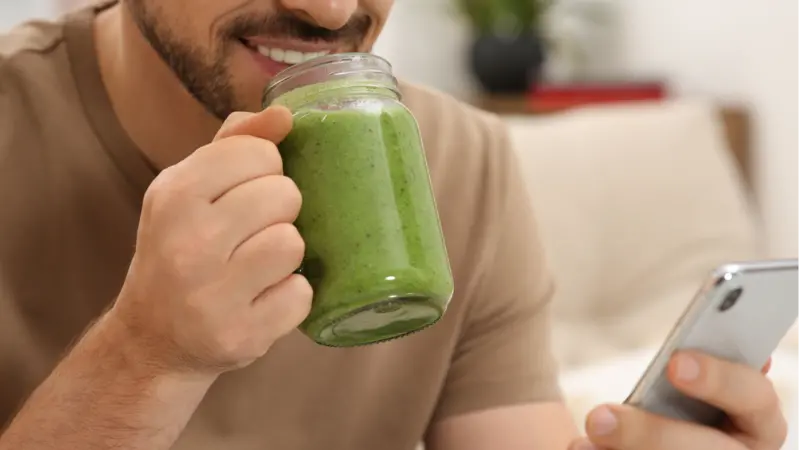 Happy man holding delicious fresh green smoothie Happy man holding delicious fresh green smoothie