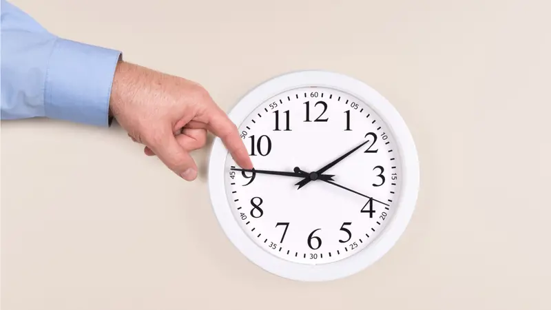 A man uses his finger to push back the time on a clock A man uses his finger to push back the time on a clock