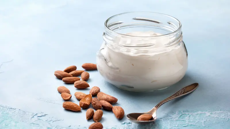 Almond yogurt in a glass jar on a blue concrete background Almond yogurt in a glass jar on a blue concrete background
