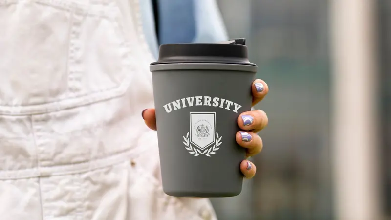 Woman holding a cup that says University