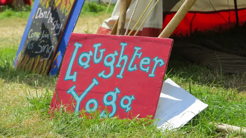 A sign advertising Laughter and Yoga leaning against a tent