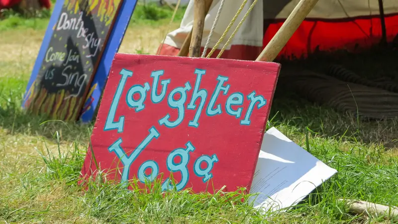 A sign advertising Laughter and Yoga leaning against a tent A sign advertising Laughter and Yoga leaning against a tent