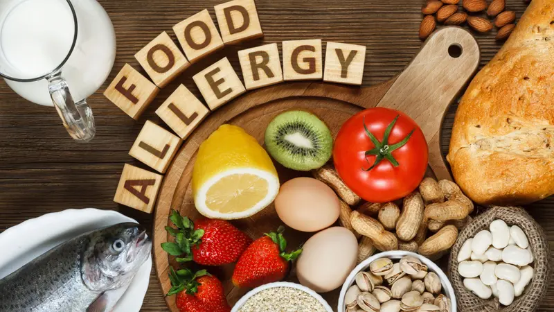 Allergy food concept. Allergy food as almonds, milk, pistachios, tomato, lemon, kiwi, trout, strawberry, bread, sesame seeds, eggs, peanuts and bean on wooden table