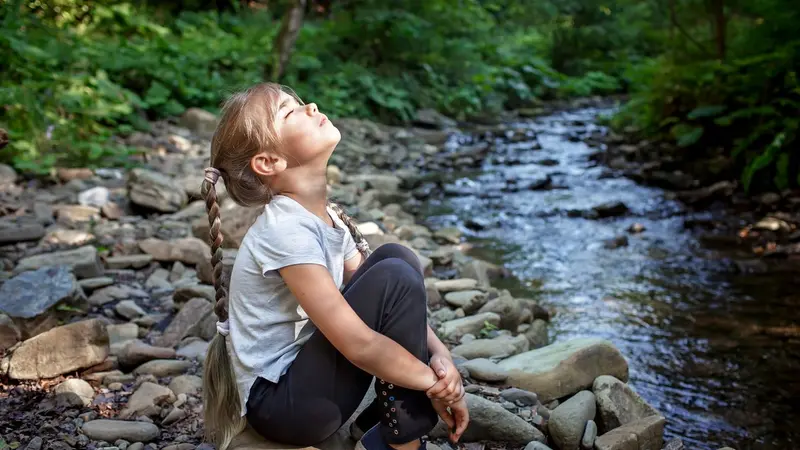 Girl sitting on side of a stream