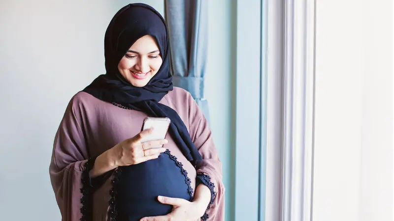 Young pregnant arab woman in hijab using her mobile phone Young pregnant arab woman in hijab using her mobile phone