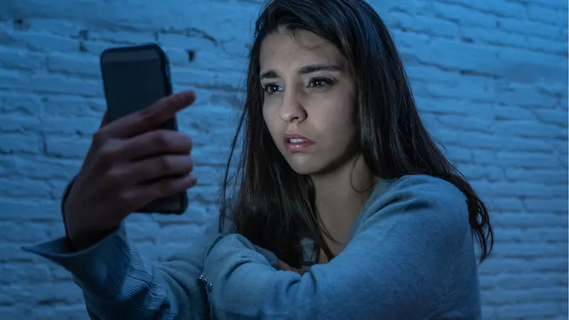 Portrait of young woman on the floor at night stressed and worried on smart mobile phone