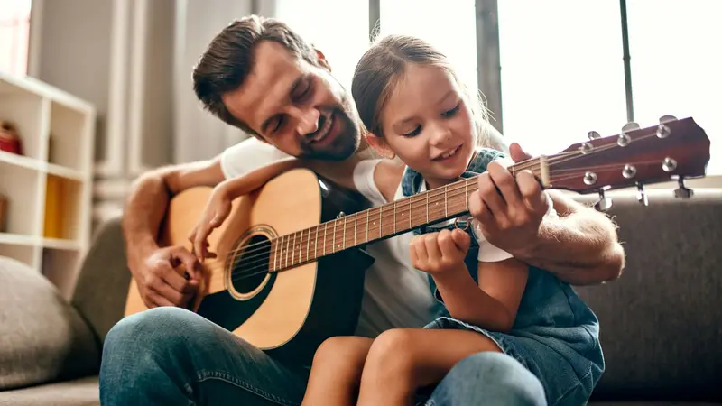 Man playing guitar with little girl