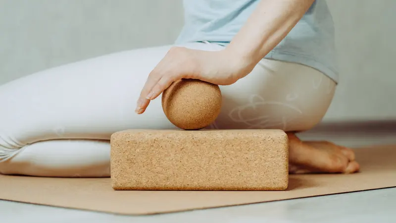 Side view of person doing palmar fascia release with a large cork ball on a cork block Side view of person doing palmar fascia release with a large cork ball on a cork block