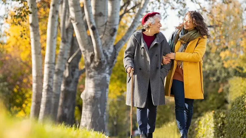 Happy woman and smiling grandma walking in autumn park.