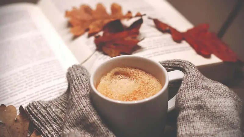 Book and hot beverage with Fall leaves