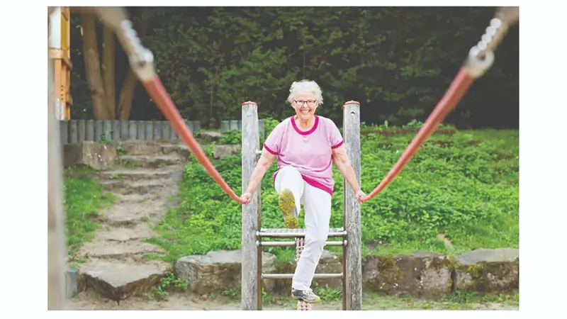 Older woman walking across a rope bridge Older woman walking across a rope bridge