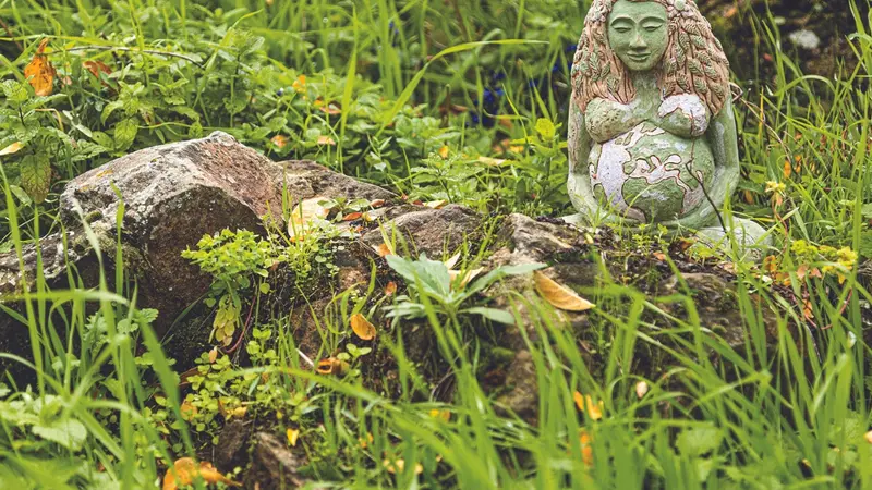 Statue of Gaia or Gea pregnant among the vegetation of a garden