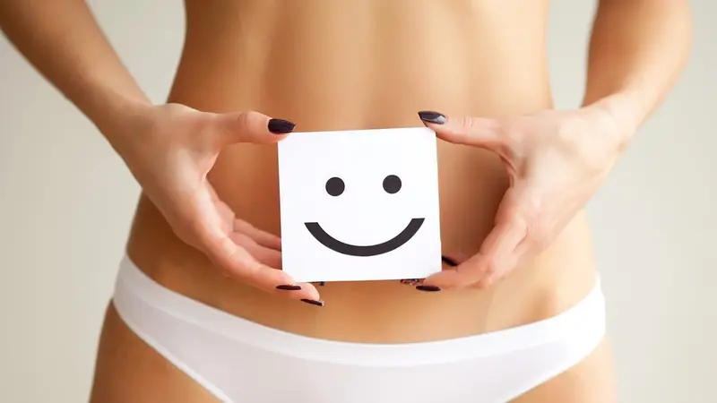 Woman holding paper with smile mark over her stomach Woman holding paper with smile mark over her stomach