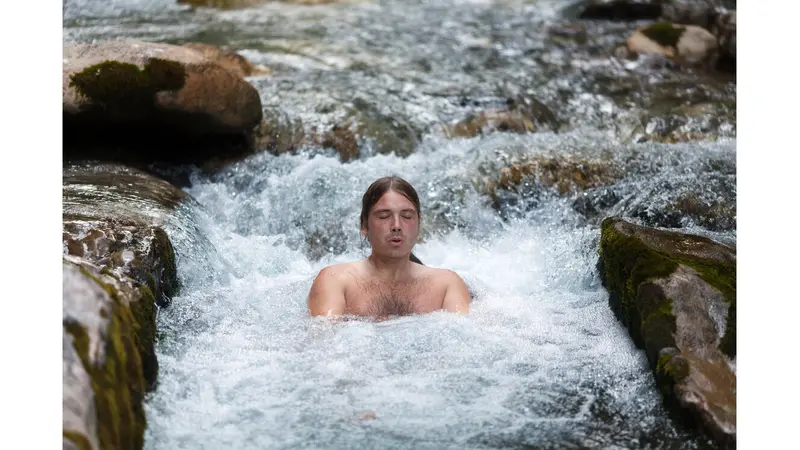Man sitting in cold river water Man sitting in cold river water