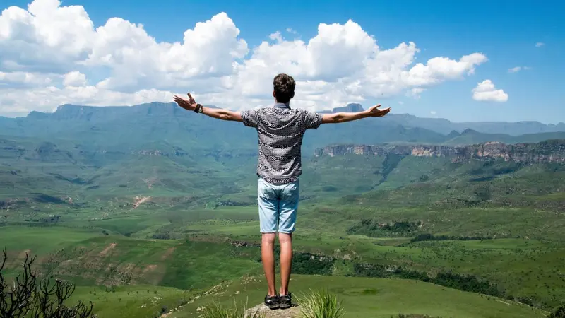 Freedom, man with outstretched arms looking over valley Freedom, man with outstretched arms looking over valley