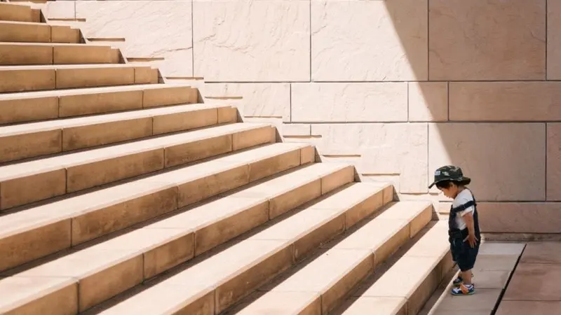 Child standing at the bottom of a great staircase Child standing at the bottom of a great staircase