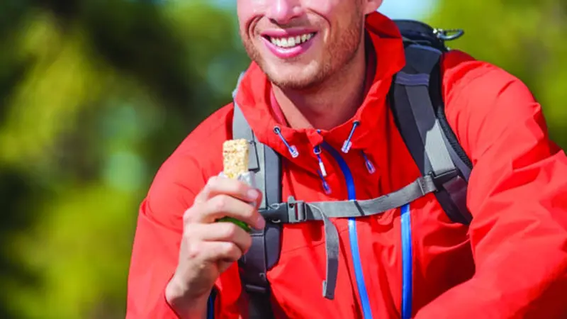 A man smiling as he holds up his food bar, clearly enjoying the moment A man smiling as he holds up his food bar, clearly enjoying the moment