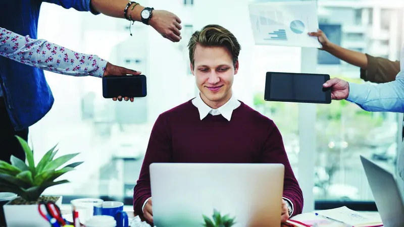 A man at his computer surrounded by extended arms representing stressors A man at his computer surrounded by extended arms representing stressors