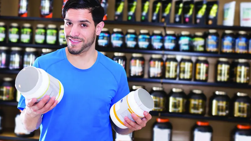 A man holding a supplement powder jars A man holding a supplement powder jars