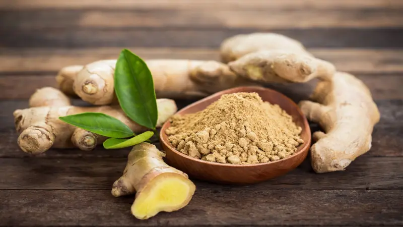 Ginger root and ginger powder in a bowl Ginger root and ginger powder in a bowl