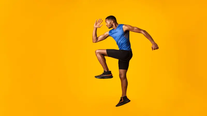 Full length portrait of muscular man with high knee, lifting leg and waving arm Full length portrait of muscular man with high knee, lifting leg and waving arm