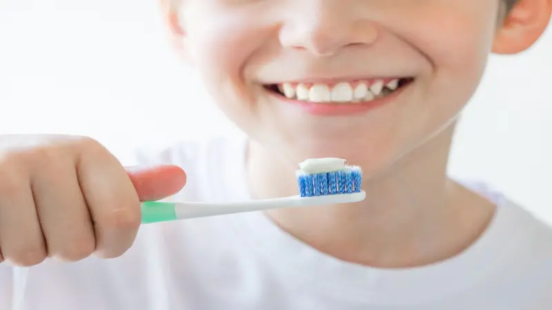 Boy holding a toothbrush in his hand, brushing teeth with fluoride toothpaste Boy holding a toothbrush in his hand, brushing teeth with fluoride toothpaste
