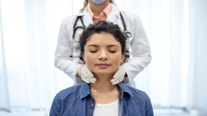 Endocrinologist examining throat of young woman in clinic. Endocrinologist examining throat of young woman in clinic.