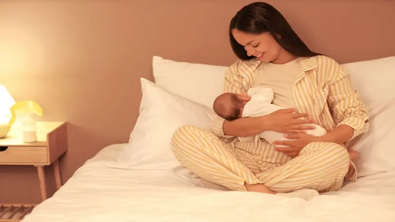 Mother breastfeeding infant in bed