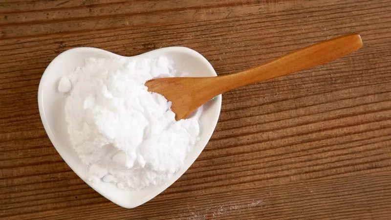 Backing soda in a heart-shaped bowl and wooden spoon Backing soda in a heart-shaped bowl and wooden spoon