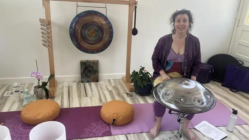 Meet your Teacher Shamanic Sound Jorney with Cacao person with gong, handpan, yoga mat & cushions