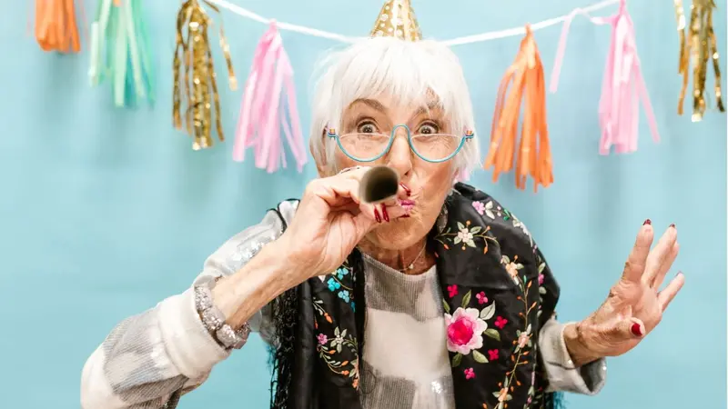 Older woman celebrating with a paper horn Older woman celebrating with a paper horn