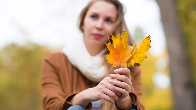 Woman holding golden maple leaves