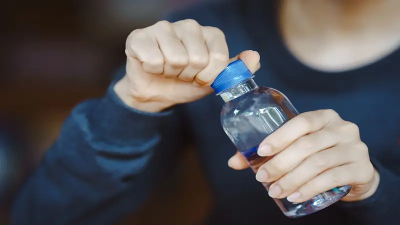 close-up hands uncapping plastic waterbottle close-up hands uncapping plastic waterbottle