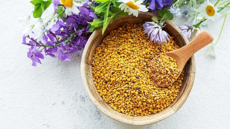 Bee pollen (not propolis) in a bowl with purple and white wildflowers