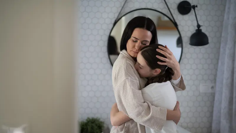 mother and daughter hug in home bathroom