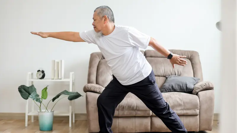 retired man doing yoga in his living room