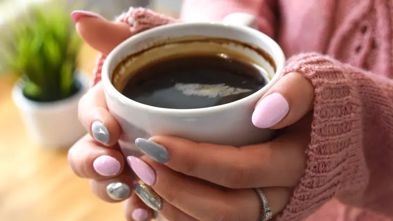 woman's hands holding a warm cup of coffee